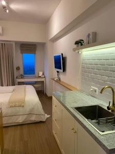 a kitchen with a sink and a bed in a room at Camaya at tanglin apartement in Lontar