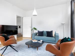 ein Wohnzimmer mit einem blauen Sofa und 2 Stühlen in der Unterkunft Sanders Leaves - Pleasant Four-Bedroom Apartment In Downtown Copenhagen in Kopenhagen