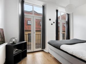 a bedroom with a bed and large windows at Sanders Leaves - Pleasant Four-Bedroom Apartment In Downtown Copenhagen in Copenhagen