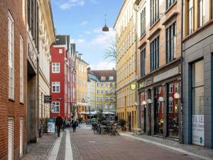 a city street with buildings and people walking down the street at Sanders Leaves - Pleasant Four-Bedroom Apartment In Downtown Copenhagen in Copenhagen
