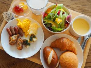 einen Tisch mit Teller mit Speisen, Salat und Brot in der Unterkunft Hotel Gee Haive in Mishima