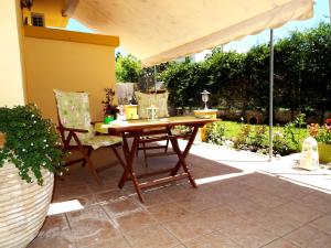 una mesa de madera y sillas bajo una sombrilla en el patio en Heliofili, en Finikounta