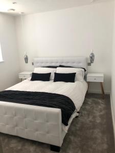 a white bedroom with a large white bed with black pillows at Contemporary 2 bedroom eco home with a twist in Marton