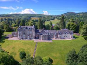 an aerial view of a large house on a green field at Lomond Castle Penthouse in Luss