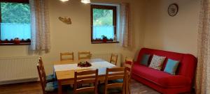 ein Esszimmer mit einem Tisch und einem roten Sofa in der Unterkunft Chalupa Maršíkov 120 in Velké Losiny