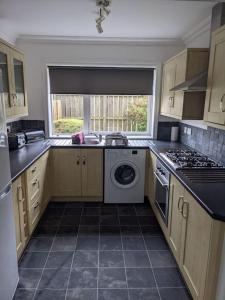 a kitchen with a washing machine and a window at Teith court apartment with private parking. in Stirling