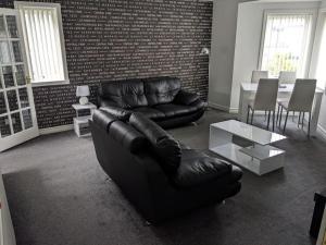 a living room with a leather couch and a table at Teith court apartment with private parking. in Stirling