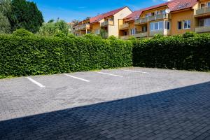 a parking lot in front of a hedge at Apartmány Gulliver in Mikulov