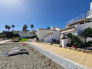 a house on the beach with a bench on the sand at Apartments Bahia Dorada in Estepona