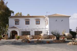 a white house with a lot of plants in front of it at Hotel Rural La Paloma in Villanueva de Tapia