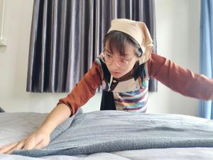 a young girl is trying to fix a bed at เกสต์เฮาส์ชูบีมา Guesthouse Chubeema Coffee & Tea in Ban Mai Ngae