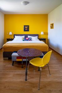 1 dormitorio con cama, mesa y pared amarilla en Apartmány Gulliver, en Mikulov
