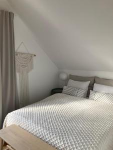 - une chambre avec un lit et une couette blanche dans l'établissement Domki ROSSE niedaleko plaży, à Jastrzębia Góra