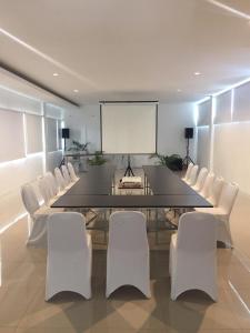 a dining room with a large table and white chairs at Red Orchid Hotel by Sajiwa in Semarang