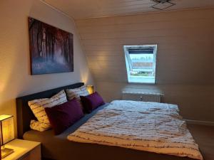 een slaapkamer met een bed met paarse kussens en een raam bij Ferienwohnung Carola in Altenburg