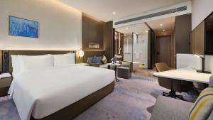 Crowne Plaza Wuhan Development Zone, an IHG Hotel في ووهان: غرفة في الفندق مع سرير أبيض كبير ومكتب