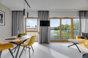 a living room with a table and chairs and a couch at Downtown Apartments Nadmotławie Riverside & Gym in Gdańsk