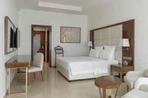 a bedroom with a white bed and a table and chair at Pyramid Continental Hotel in Juba