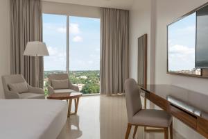 a hotel room with a bed and chairs and windows at Pyramid Continental Hotel in Juba