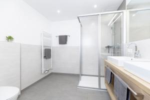 een badkamer met een douche, een wastafel en een toilet bij Apart Alina in Schwendau