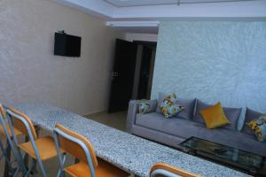 a living room with a couch and a table with chairs at Soleil & Piscine BOUZNIKA in Bouznika