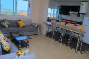 a living room with a couch and a table with chairs at Soleil & Piscine BOUZNIKA in Bouznika