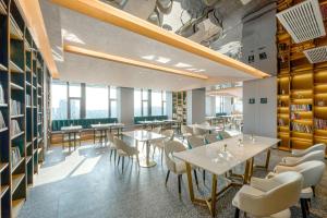 a restaurant with white tables and chairs and windows at Atour Hotel Taixing Municipal Government Drum Tower Xintiandi in Taizhou