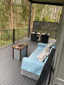 a bed on a deck with a table on a porch at 424 Trees Tiny Home in Tallebudgera