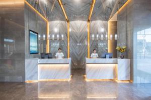 two people sitting at a desk in a lobby at Atour Hotel Xiaolan Zhongshan in Zhongshan