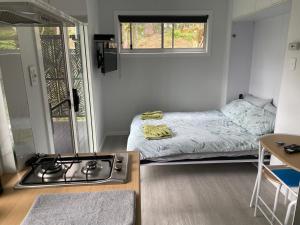 a kitchen with a stove and a bed in a room at 424 Trees Tiny Home in Tallebudgera