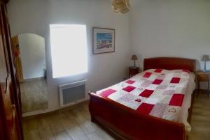a bedroom with a bed with a red and white quilt at Le Baco, gîte à la ferme in Coublevie