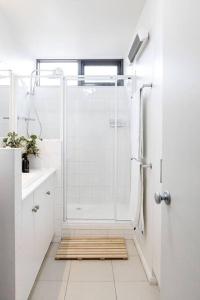 a white bathroom with a shower and a sink at Iconic Mid-century modern, waterfront apartment in Geelong