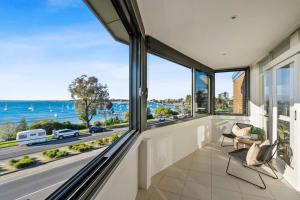 a living room with large windows and a view of the ocean at Iconic Mid-century modern, waterfront apartment in Geelong