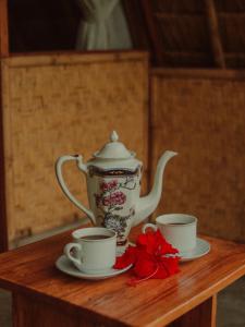 ムンドゥックにあるDa'kayu Glampingの木製テーブルの茶鍋と2杯