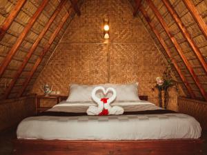 un conejo de peluche blanco sentado en la parte superior de una cama en Da'kayu Glamping, en Munduk
