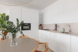 Playa de MarにあるMarsalada - Ground floor front line beach apartmentの白いキッチン(テーブル、花瓶付)