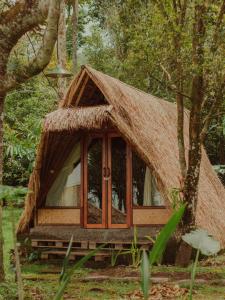 uma pequena cabana com telhado de palha na floresta em Da'kayu Glamping em Munduk