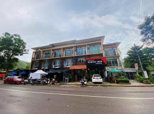 เกสต์เฮาส์ชูบีมา Guesthouse Chubeema Coffee & Tea في Ban Mai Ngae: مبنى كبير به دراجات نارية متوقفة أمامه