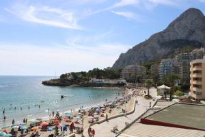 uma praia com guarda-sóis e pessoas na água em INMO WEAVER 318 FM 1ª línea de playa em Calpe