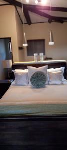 - un lit avec des oreillers blancs et un oreiller vert dans l'établissement Bee-Eater Cottage, DaGama Dam, à White River