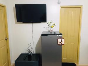 a room with a refrigerator and a tv on the wall at One Spatial Iloilo Two Bedroom Condominium Unit with Pool and Gym in Iloilo City