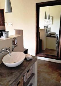 une salle de bain avec un lavabo et un grand miroir dans l'établissement Bee-Eater Cottage, DaGama Dam, à White River 18 autres photos