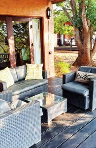 une terrasse couverte avec des meubles en osier et une table en verre dans l'établissement Bee-Eater Cottage, DaGama Dam, à White River