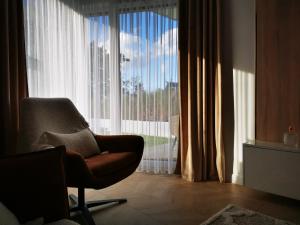 a living room with a chair and a large window at Gold Apartment B29 Let's Sea Baltic Park Gąski in Gąski