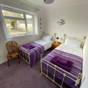 two beds in a room with a window at Agapanthus Bed & Breakfast - Fraddam in Hayle