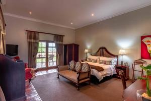 a large bedroom with a bed and a chair at Mooiplaas Guesthouse in Oudtshoorn