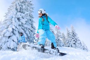 a woman riding a snowboard down a snow covered slope at Residenza Riva Wellness Apartment Spa in Abetone