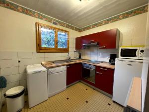 uma cozinha com armários vermelhos e um frigorífico branco em Ty Menez 2 - Chalet sur les pistes em La Clusaz