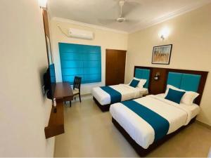 um quarto de hotel com duas camas e uma secretária e uma televisão em The Oval House - Approved by Kerala Tourism em Cochin