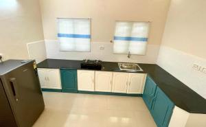 a kitchen with green and white cabinets and a sink at The Oval House - Approved by Kerala Tourism in Cochin
